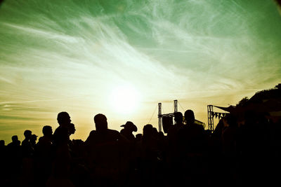 Silhouette people at music concert against sky during sunset