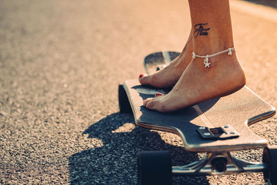 Low section of woman skateboarding on road