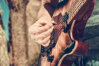 Midsection of man playing guitar