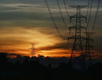 Low angle view of silhouette electricity pylon against sunset sky