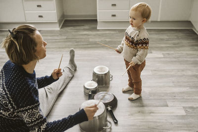 Mother and daughter playing with chopsticks and utensils in kitchen