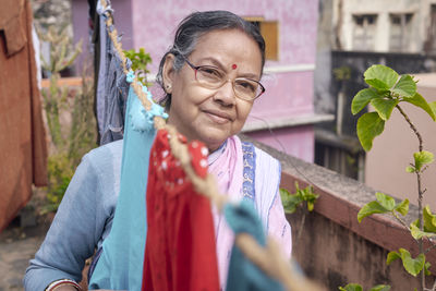 Portrait of a simple looking mature indian woman in building rooftop during hanging up of laundry