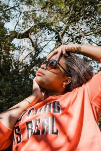 Low angle view of woman posing against tree