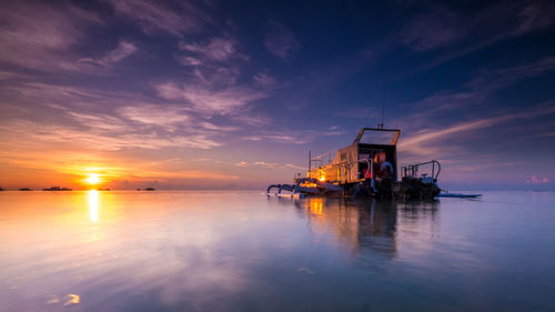 Fishing boat in sea against sky during sunset