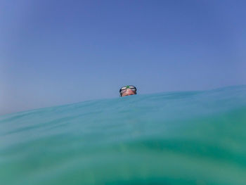 Person swimming in sea against clear blue sky