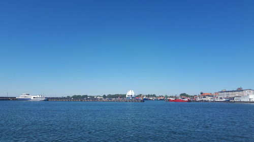 Sailboats in sea against clear blue sky