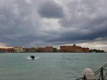 Buildings by sea against sky