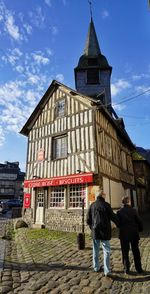 Rear view of people walking at temple against sky