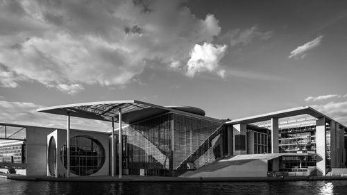 Buildings by river against sky