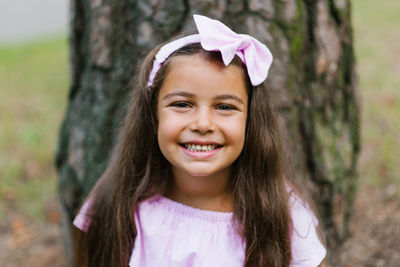 Portrait of a cute little girl with a wide and beautiful smile in a pink dress