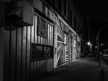 Illuminated street amidst buildings at night