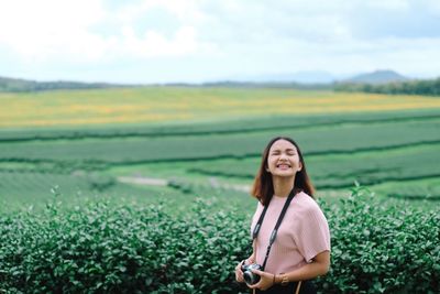 Young woman standing against agricultural field