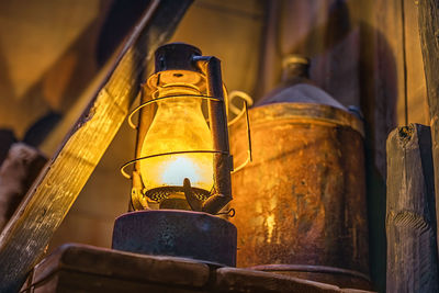 Lit rusty storm lamp and vintage equipment in abandoned workshop or shipyard