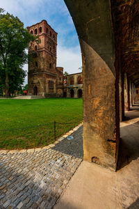 Old building by footpath in city against sky