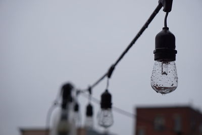 Low angle view of lighting equipment hanging against clear sky