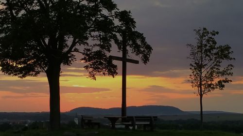 Trees on landscape against sky during sunset