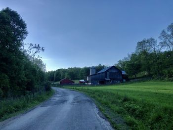 Road amidst houses and trees against sky