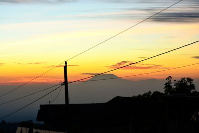 Silhouette electricity pylon against sky during sunset