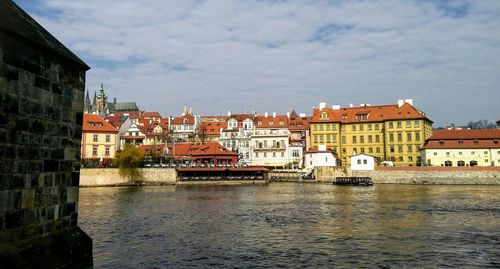 Buildings by river against sky in city