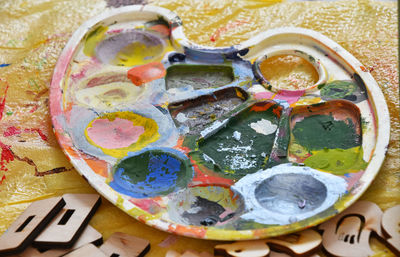 High angle view of messy palette on yellow plastic