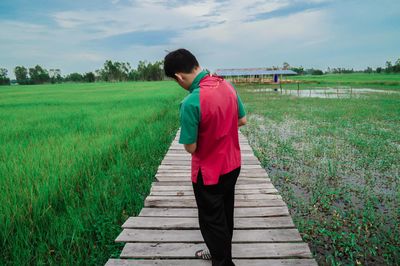 Full length of man standing on boardwalk at farm