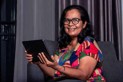 Portrait of smiling woman using digital tablet at home