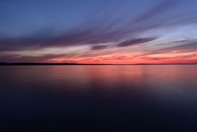 Tranquil scene at sunset blue sky in the twilight glow over calm water surface in gloomy silence