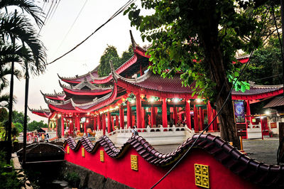 Red temple by building against sky