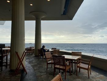 Chairs and tables on beach against sky