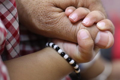 Cropped image of baby holding parent hand