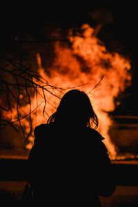 Rear view of silhouette woman standing against bonfire