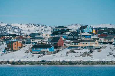 Townscape by sea against clear blue sky