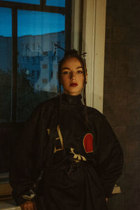 Portrait of young woman standing against wall