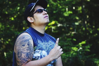 Young man pointing against trees