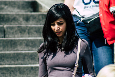 Young woman looking down while standing outdoors