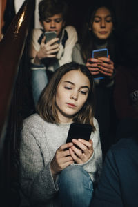 Friends using mobile phone while sitting on steps