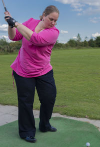 Full length of young woman standing on golf course
