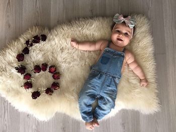 Directly above shot of baby girl lying by roses arranged in number 6 on rug