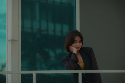 Portrait of a young woman looking through window