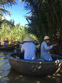 Rear view of people sitting on boat against trees