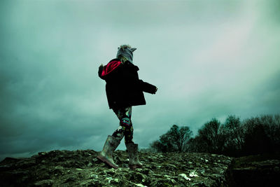 Rear view of woman standing on field against sky