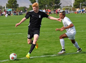 Full length of friends running on soccer field