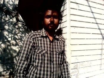Portrait of young man standing against wall