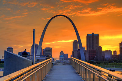 View of bridge and buildings against orange sky during sunset