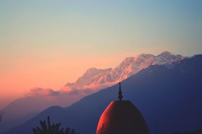 Dome of a temple with the backdrop of the himalayan ranges at sunset