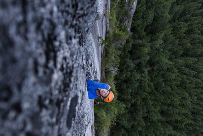 Climber popping out his head looking up while climbing above forest