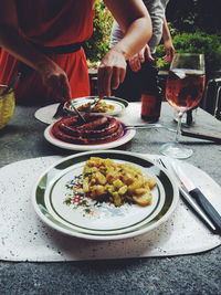 Midsection of woman having sausage on table