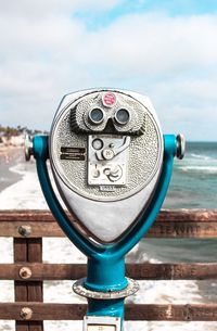 Close-up of coin-operated binoculars against sea