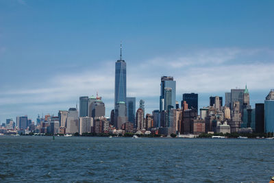 Sea by modern buildings in city against sky