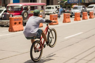 Rear view of man riding bicycle on road